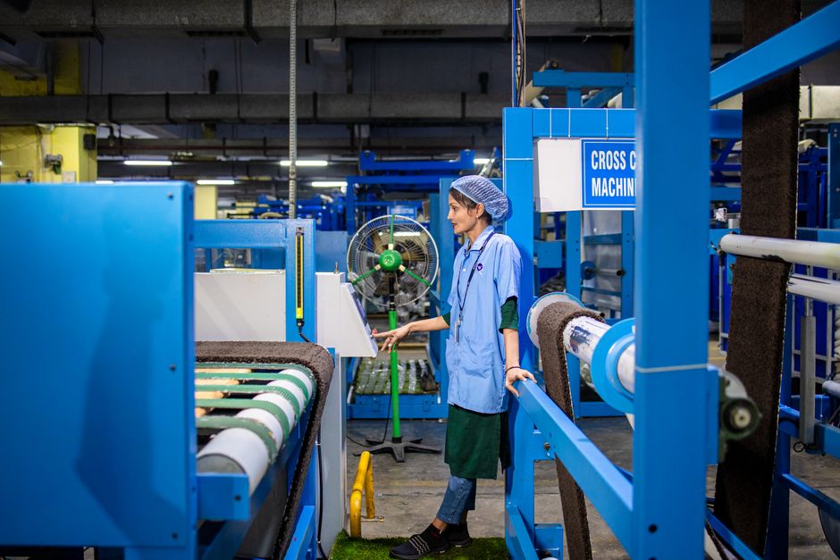 A female worker operating machinery in a textile factory, focused on production.
